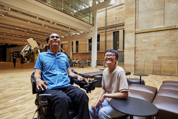Man who uses a wheelchair and friend in Hintze Hall